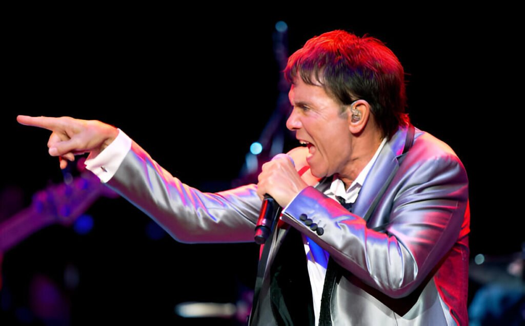 Cliff Richard performing live at the Royal Albert Hall with elegant stage lighting and an enthusiastic