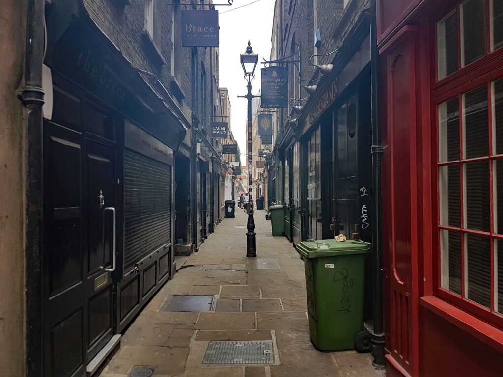 A narrow Victorian alleyway with old-fashioned shopfronts in London.