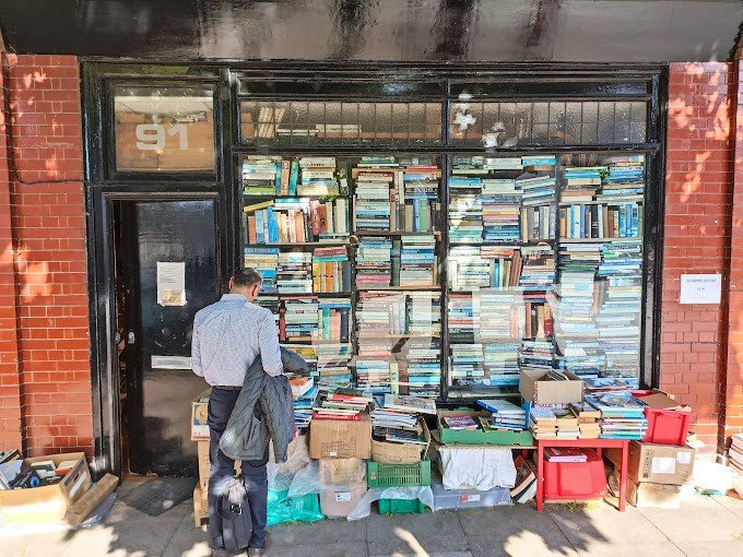 A narrow bookstore filled with stacks of books from floor to ceiling