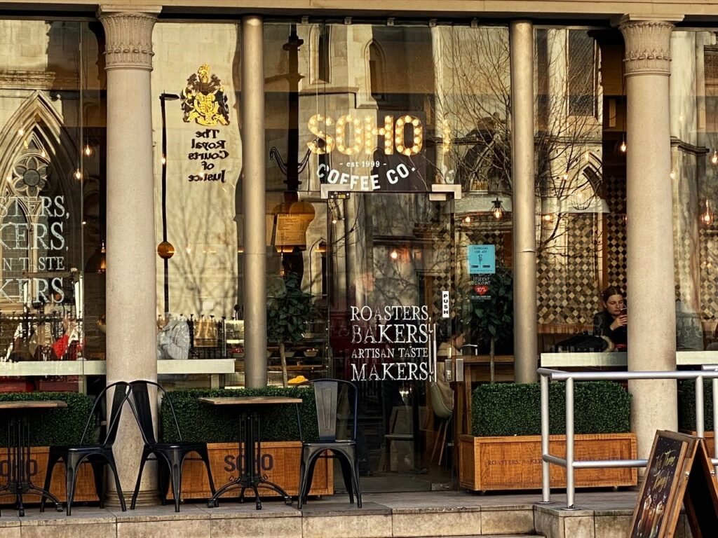 Soho Coffee shop near the Royal Courts of Justice, featuring outdoor seating with a view of the grand Gothic architecture