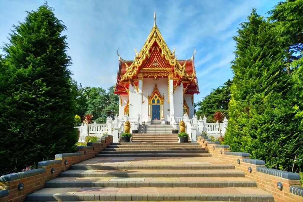 A stunning Thai temple with a golden roof, surrounded by gardens