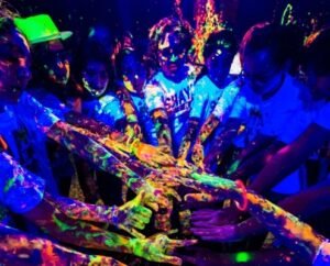 People enjoying a Neon Paint Fight at Splash Art in London, splashing glowing paint under UV lights in a fun and colourful setting